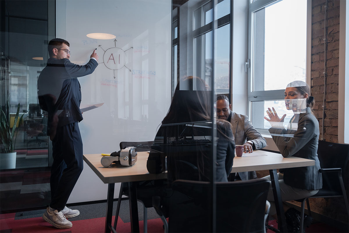 Teammeeting im Büro mit Präsentation zu KI am Whiteboard und AI-Skizze.