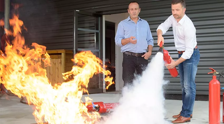 Die Praxis des Feuerlöschens wird mit einem Feuerlöscher durch den Geschäftsführer erprobt. © Adobe Stock, auremar