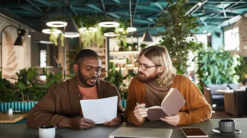 Zwei Mitarbeiter sitzen in einem Green Office und besprechen Maßnahmen, um ihr Büro noch nachhaltiger zu gestalten. © Adobe Stock, Seventyfour